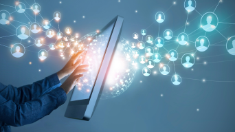 Eine Person berührt ein Tablet, auf dessen Bildschirm holografische Verbindungen entstehen, die eine globale digitale Vernetzung symbolisieren. Blaue und weiße Knoten mit Benutzersymbolen sind durch Linien verbunden und bilden ein Netzwerk um einen leuchtenden Globus.